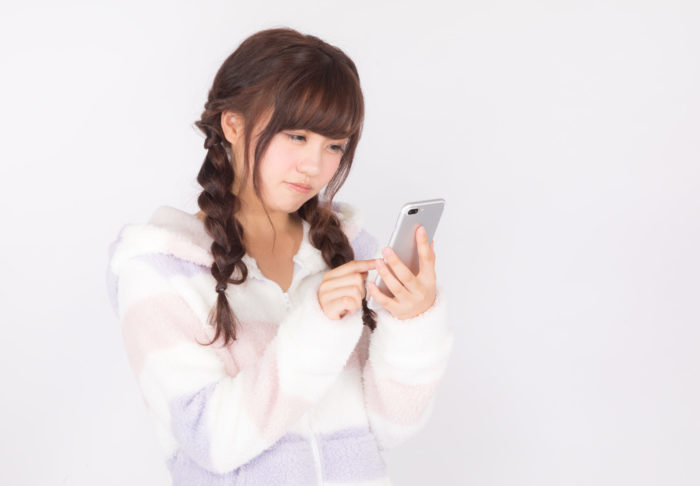 スマホ画面を見て落ちこむj女性
