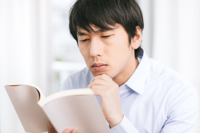 難しそうな表情で読書する男性